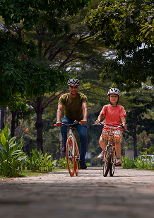 Couple riding bicycles on a path through a lush green park